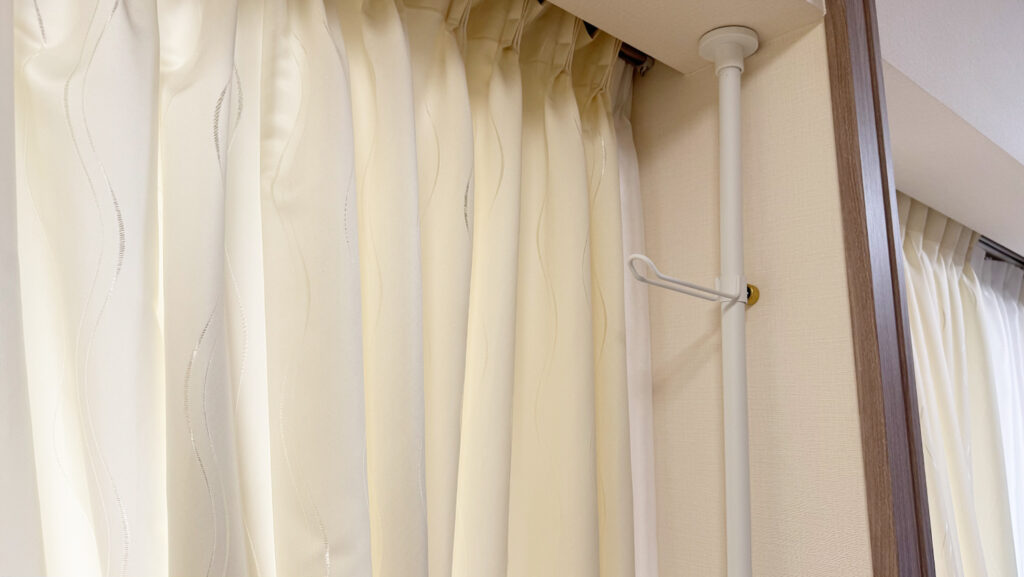 白いポールがカーテン横に設置されている写真